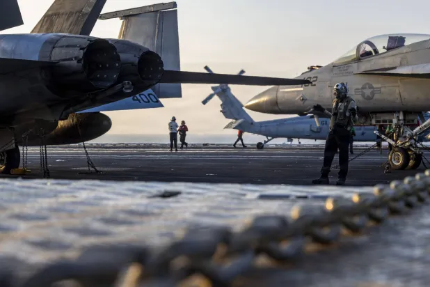 صورة نشرتها البحرية الأميركية أمس من فني يوجه مقاتلة على سطح حاملة الطائرات «أبراهام لينكولن» في بحر العرب (البحرية الأميركية)