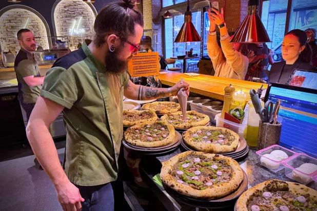 László Bárdossy, head chef of the Neverland Pizzeria adds topping on the restaurant's Roman-era pizza in Budapest, Hungary, on Feb. 11, 2026. (AP) 