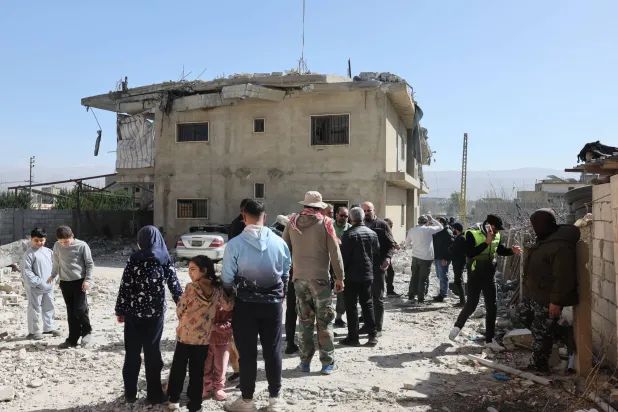 عدد من المواطنين يتفقدون الأضرار الناجمة عن قصف مبنى في بلدة تمنين في البقاع مساء الجمعة (إ.ب.أ)