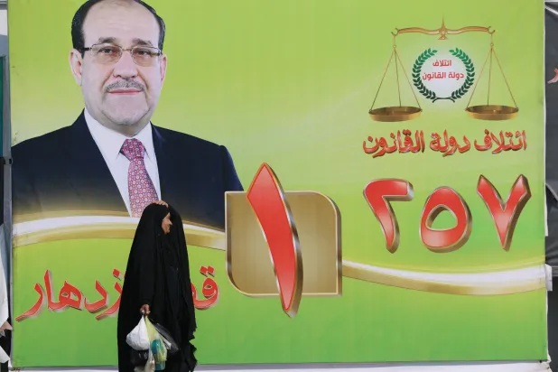 امرأة تمر أمام لوحة إعلانية انتخابية تحمل صورة رئيس الوزراء العراقي السابق نوري المالكي في وسط بغداد يوم 19 أكتوبر 2025 (أ.ف.ب)