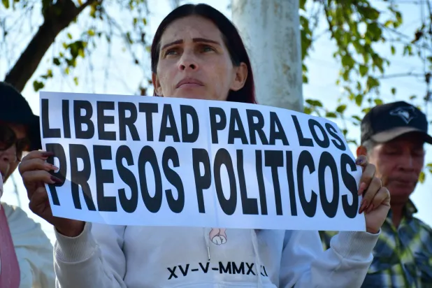 امرأة ترفع لافتة كُتب فيها «الحرية للسجناء السياسيين» خلال مظاهرة للمطالبة بإطلاق السجناء السياسيين الفنزويليين أمام سجن توكويتو قرب فالنسيا بفنزويلا (أ.ف.ب)