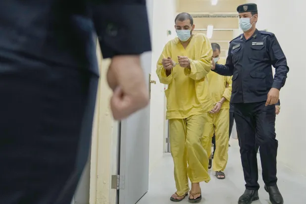 رجل أمن عراقي مع عناصر من «داعش» في «سجن الكرخ» ببغداد (أ.ب)