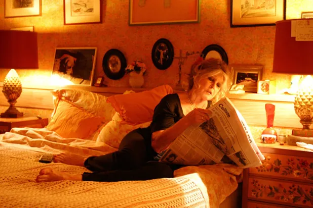 بريجيت باردو في منزلها بباريس تقرأ صحيفة «لو فيغارو» على سريرها (غيتي)