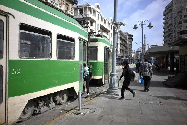 People run to catch a tram in the coastal city of Alexandria, on February 18, 2026. (Photo by Khaled DESOUKI / AFP)