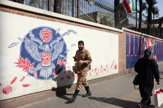 جندي إيراني يمر بجوار جدارية مناهضة للولايات المتحدة في طهران (إ.ب.ا) 