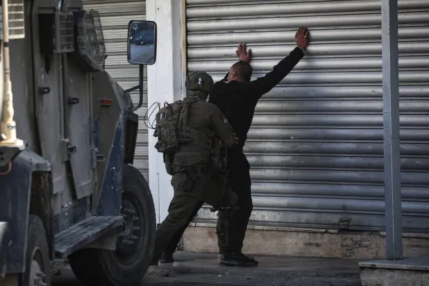 جندي إسرائيلي يفتش فلسطينياً خلال اقتحام القوات الإسرائيلية مخيماً قرب نابلس بالضفة الغربية (أرشيفية - د.ب.أ)