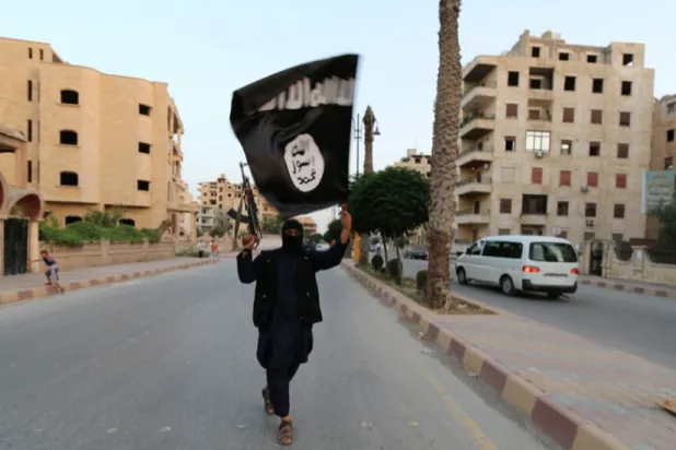 FILE PHOTO: A member loyal to the Islamic State waves an ISIS flag in Raqqa, Syria June 29, 2014. REUTERS/Stringer/Files