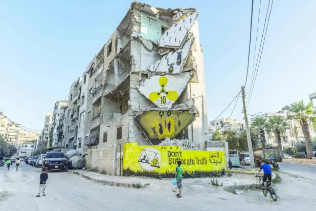 20 August 2023, Syria, Idlib: Children play next to a destroyed building with a mural painted on it during a commemoration event for the 10th anniversary of the Ghouta chemical attack. (Anas Alkharboutli/dpa)