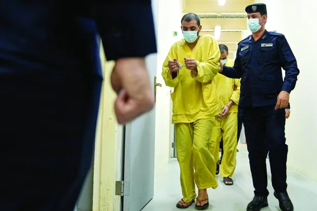 رجل أمن عراقي مع مشتبهين بالانتماء إلى «داعش» في سجن الكرخ ببغداد (أ.ب)