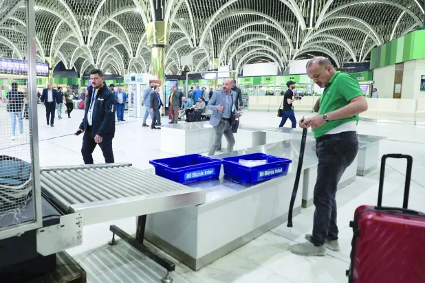 A passenger takes his belongings after inspection at the departure hall of Baghdad's International airport on March 14, 2023. (Photo by AHMAD AL-RUBAYE / AFP)