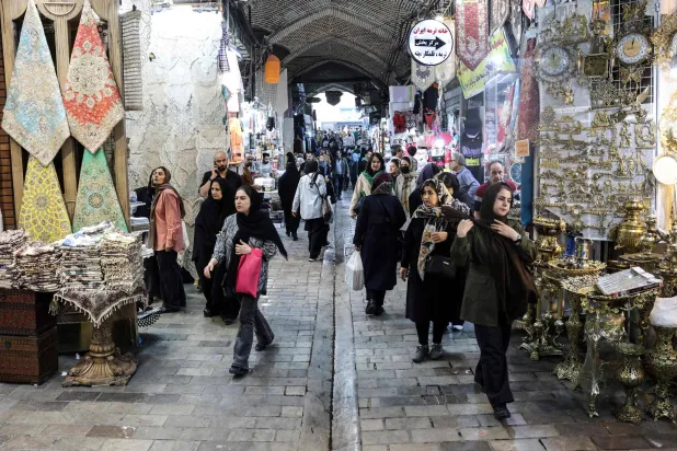 Iranians walk through Tehran's Grand Bazaar on February 24, 2026. (AFP)