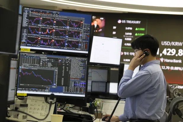 متداول كوري جنوبي يعمل أمام شاشات تعرض مؤشرات الأسهم في بنك هانا بسيول (إ.ب.أ)