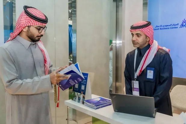 A beneficiary looks at a brochure for the Saudi Business Center (Asharq Al-Awsat)