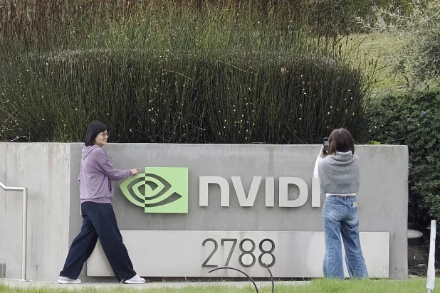 شخصان يلتقطان صوراً لشعار شركة «إنفيديا» خارج مقرها الرئيسي في سانتا كلارا بكاليفورنيا (إ.ب.أ)