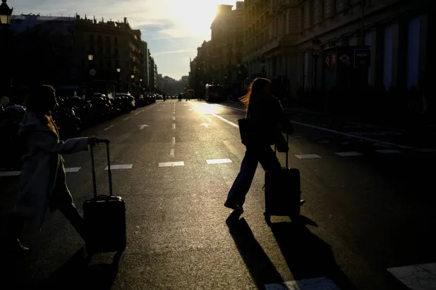 سياح يجرون أمتعتهم عند وصولهم إلى ساحة كاتالونيا في برشلونة (رويترز)