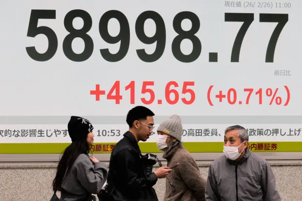 مشاة يمرون أمام شاشة إلكترونية تعرض حركة الأسهم وسط العاصمة اليابانية طوكيو (أ.ب)