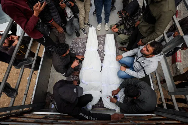 فلسطينيون بجوار جثماني شخصين قُتلا في غارة إسرائيلية على غزة يوم أمس (رويترز)