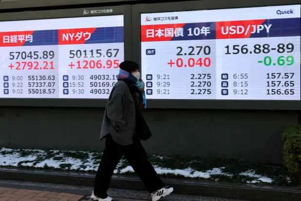 سيدة تمر أمام شاشة تعرض حركة الأسهم في وسط العاصمة اليابانية طوكيو (رويترز)