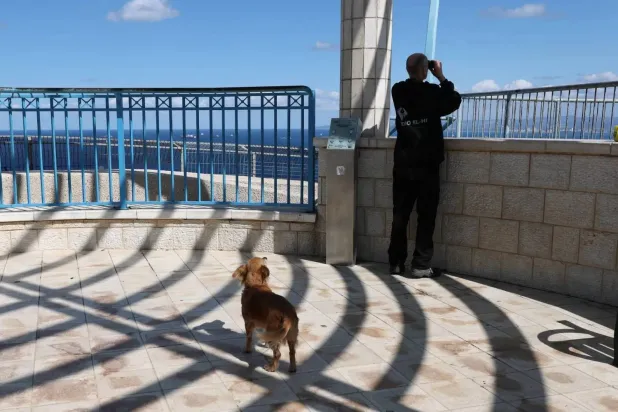 Man uses binoculars to watch the Mediterranean ahead of the expected arrival of the aircraft carrier Gerald Ford at Haifa port (EPA)