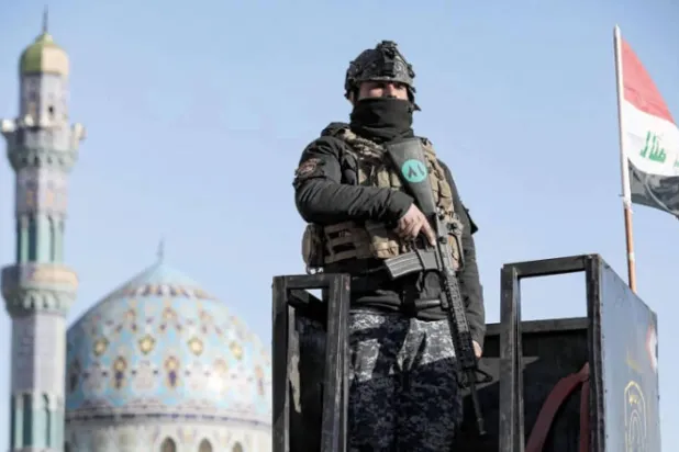 رجل أمن عراقي يقف على برج مراقبة في بغداد (د.ب.أ)