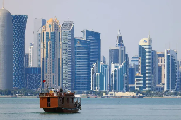 A traditional dhow boat with tourists travels on the waters of the Persian Gulf in front of the West Bay skyline in Doha, Qatar, 27 February 2026. (EPA)