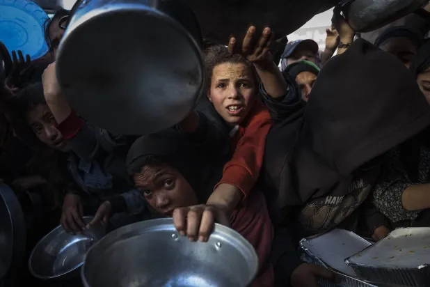 فلسطينيون خلال انتظارهم تلقي الطعام في مطبخ خيري بخان يونس جنوب قطاع غزة (أ.ف.ب)