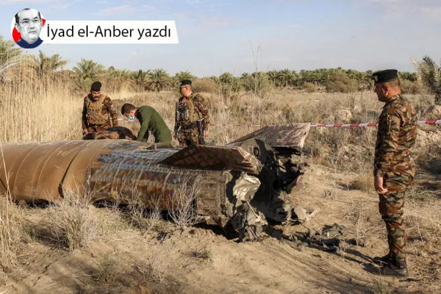 Irak İçişleri Bakanlığı bünyesindeki Patlayıcılarla Mücadele Müdürlüğü görevlileri, ülkenin orta kesimlerindeki Babil ilinin Hilla kenti yakınlarındaki Siyahe bölgesinde bir köye düşen roket yakıt tankını incelerken, 1 Mart 2026 (AFP)