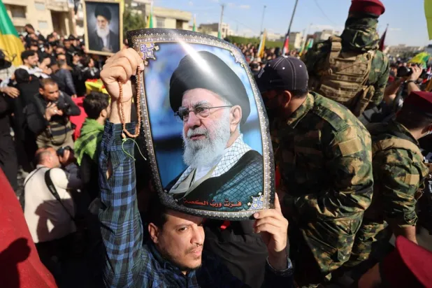 4 Mart'ta hava saldırısında öldürülen Irak Hizbullah Tugayları üyelerinin cenazesi sırasında bir kişinin taşıdığı Hamaney'in bir fotoğrafı (AFP)