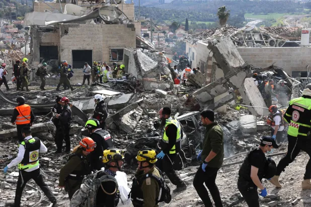 عناصر من فرق الإنقاذ الإسرائيلية بتفتيش موقع هجوم صاروخي قرب مدينة بيت شيمش، على بُعد نحو 30 كيلومتراً غرب القدس(أ.ف.ب)