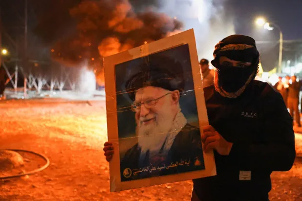 متظاهر في بغداد يحمل صورة المرشد الأعلى الإيراني علي خامنئي بعد إعلان مقتله (رويترز)