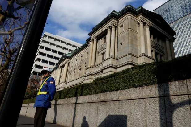 رجل أمن يمر بجوار سور مقر البنك المركزي في العاصمة اليابانية طوكيو (رويترز)