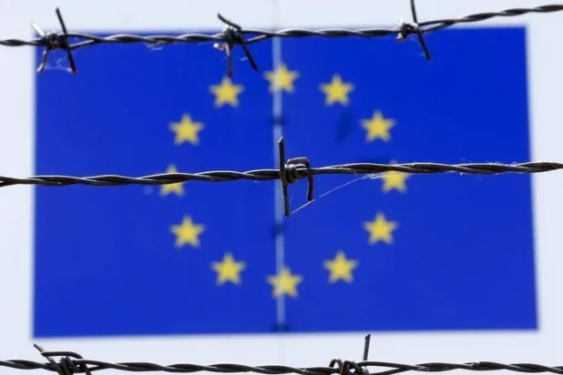 سلك شائك أمام علم الاتحاد الأوروبي (أرشيفية - رويترز)
