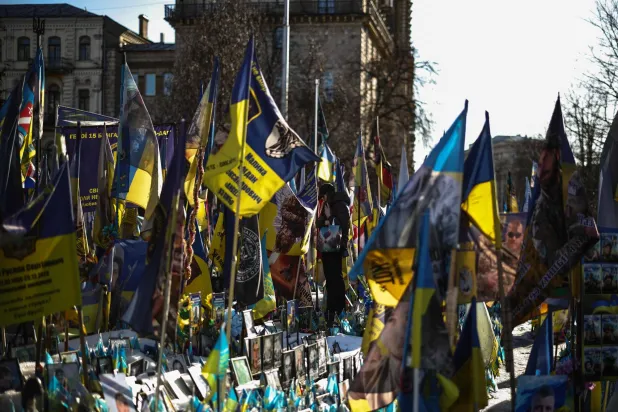 أوكرانيون يزورون نصباً تذكارياً مؤقتاً للجنود القتلى في ساحة الاستقلال بكييف الاثنين (أ.ف.ب)