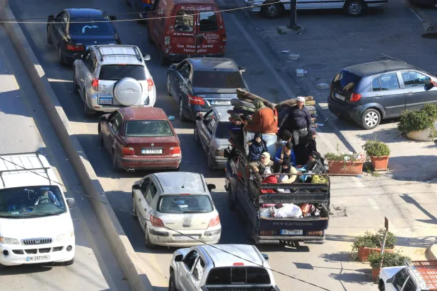 عائلة تحمّل أغراضها في حافلة على الطريق الساحلي لمدينة صيدا التي تزدحم بالسيارات الهاربة من الجنوب (أ.ف.ب)