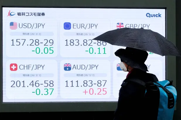 رجل ينظر إلى لوحة عرض إلكترونية تعرض أسعار صرف الين مقابل العملات العالمية الرئيسية في أحد شوارع طوكيو (أ.ف.ب)