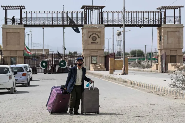 A Pakistani national walks across the Pakistan-Iran border after returning from Iran at Taftan, Balochistan province on March 2, 2026. (AFP)