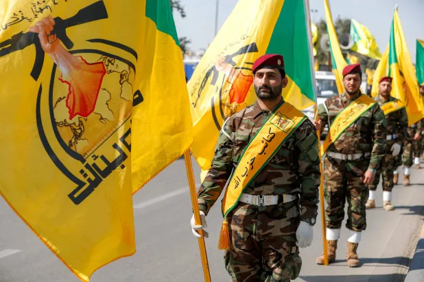 Members of Iraq's pro-Iran paramilitary group Kataib Hezbollah march with the group's banners in a funeral for slain fighters killed in a US-Israeli airstrike on their headquarters in al-Qaim near the border with Syria, during a ceremony in Baghdad on March 2, 2026. (AFP) 