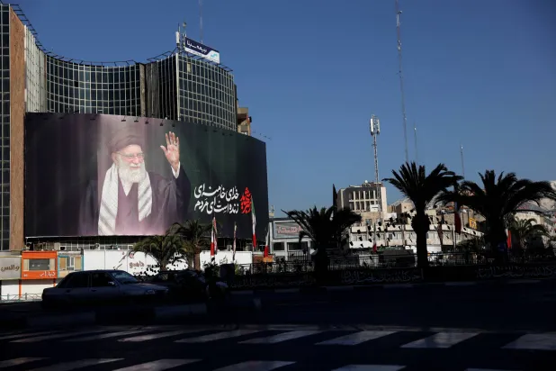سيارة تمر بجوار لوحة إعلانية للمرشد الإيراني الراحل علي خامنئي في أحد شوارع طهران بإيران بعد اغتياله في غارات جوية إسرائيلية وأميركية يوم السبت (رويترز)