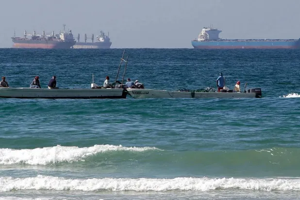 مراكب صيد صغيرة أمام ناقلات نفط عملاقة تنتظر فتح مضيق هرمز (أ.ب)