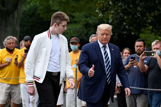 الرئيس الأميركي دونالد ترمب يسير إلى جانب نجله بارون (رويترز)