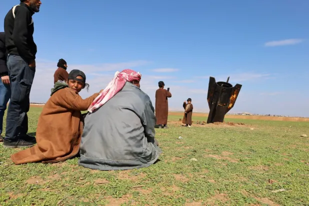 سكان قرية قزلجو بريف القامشلي شمال شرقي سوريا متجمعون عند صاروخ إيراني سقط في قريتهم الأربعاء (إ.ب.أ)