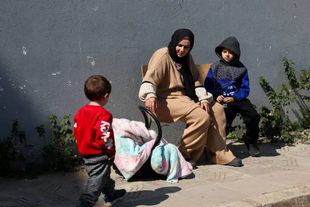 امرأة نازحة مع أطفالها تجلس خارج مدرسة في بيروت تحولت إلى ملجأ في أعقاب تصعيد عسكري بين «حزب الله» وإسرائيل (رويترز)