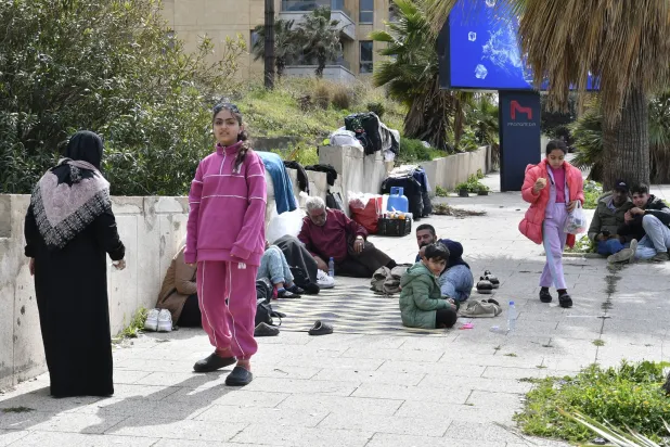 يجلس سكان نازحون على الأرض في بيروت بعد فرارهم من منازلهم بجنوب لبنان وضاحية بيروت الجنوبية (إ.ب.أ)