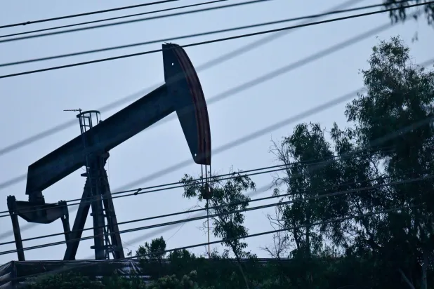 مضخة نفط تعمل في حقل مونتيبيلو النفطي خلف صف من خطوط الكهرباء في مونتيبيلو، كاليفورنيا (أ.ف.ب)