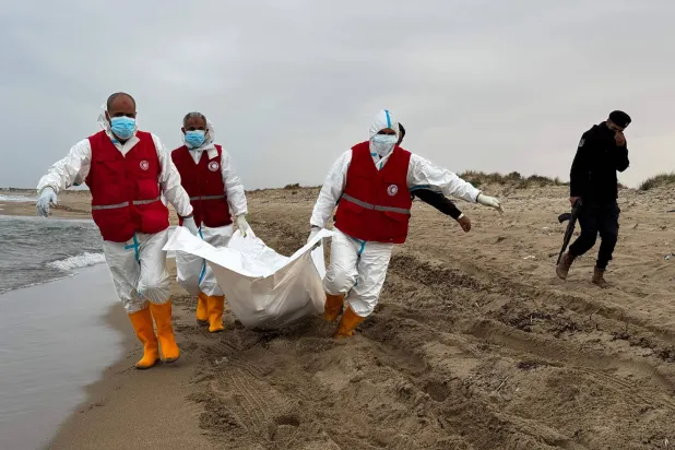 عناصر الهلال الأحمر الليبي ينتشلون جثة مهاجر سري قذفتها أمواج البحر في شاطئ شرق طرابلس (أ.ف.ب)