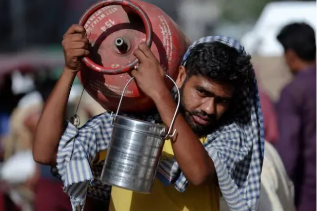 رجل يحمل قارورة غاز البترول المسال على كتفه في سوق جملة بالأحياء القديمة في دلهي (رويترز)