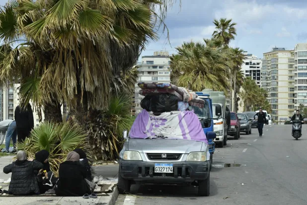 نازحون يجلسون بجوار ممتلكاتهم على رصيف في بيروت 4 مارس 2026 بعد فرارهم من جنوب لبنان والضاحية الجنوبية إثر إنذارات وغارات إسرائيلية (إ.ب.أ)