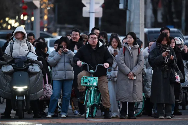 People cross a road in Beijing on March 6, 2026. (AFP)