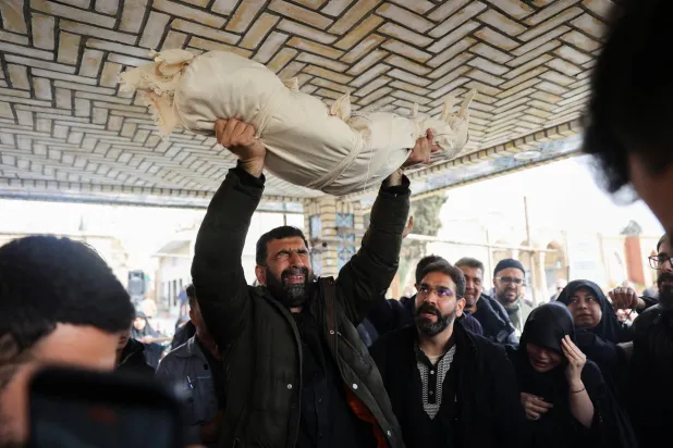 رجل يحمل جسد زينب صاحبي الطفلة البالغة من العمر عامين والتي قُتلت في غارة جوية على طهران (رويترز)