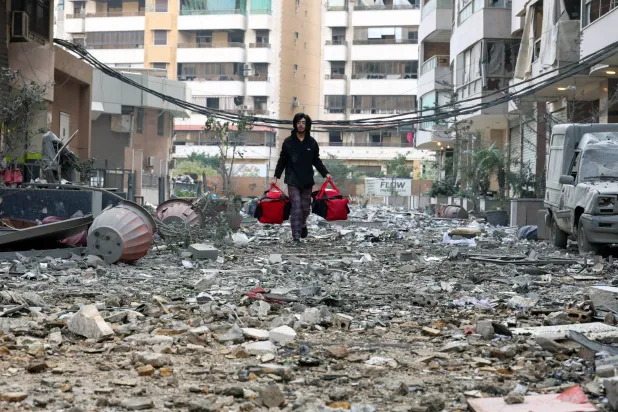 لبناني يحمل أغراضه ويغادر منطقة الشياح في العاصمة اللبنانية بيروت عقب غارات إسرائيلية (إ.ب.أ)